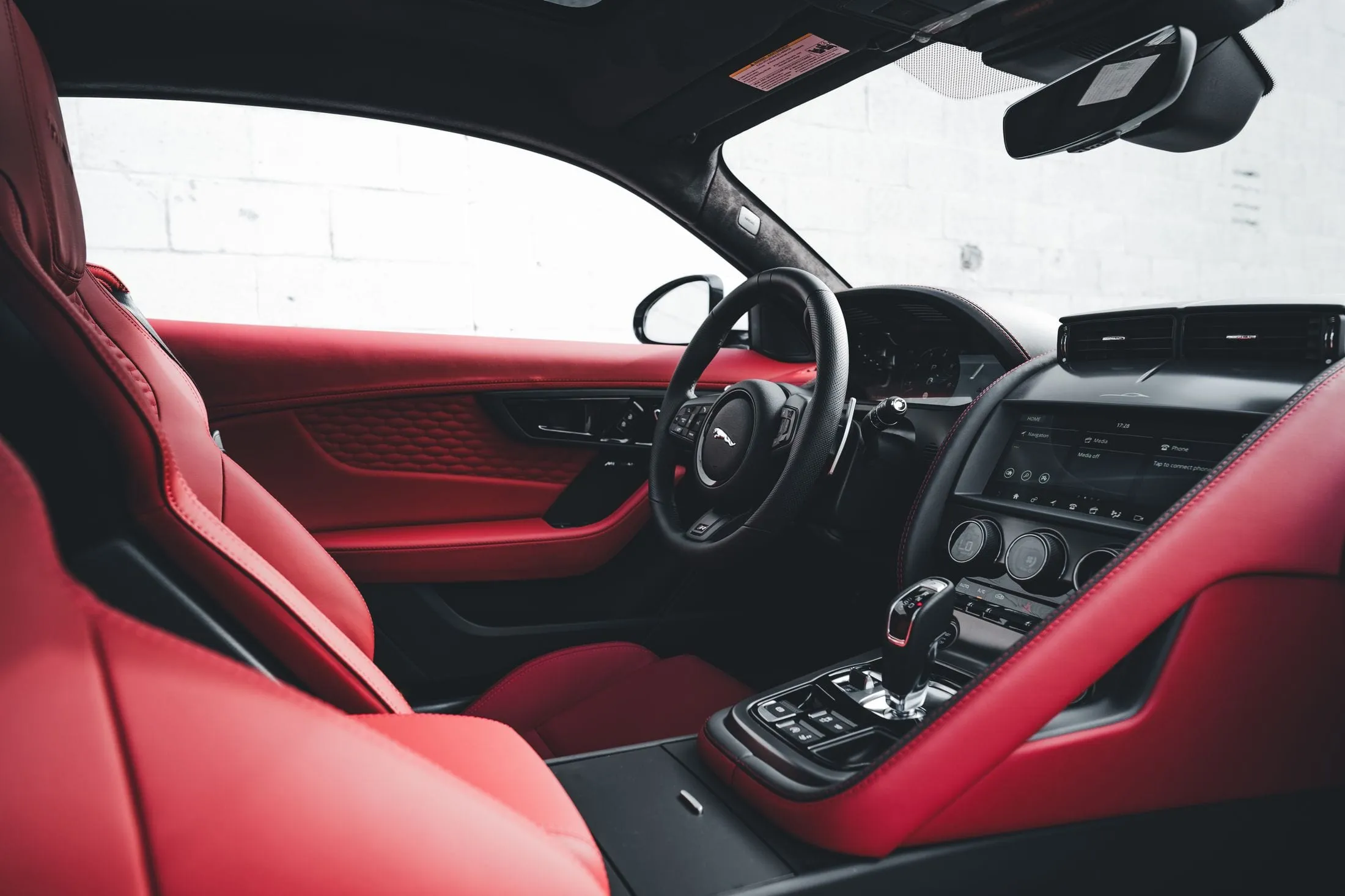 Interior de un cupé con el forro del techo en negro y la tapicería en cuero rojo con costura contrastada