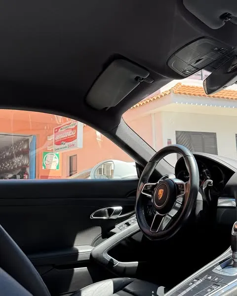 Habitáculo de un Porsche con el techo forrado en negro, visto desde el asiento del acompañante