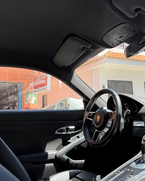 Interior de un deportivo visto desde atrás, con el forro del techo tenso y sin descolgar sobre el salpicadero y el volante