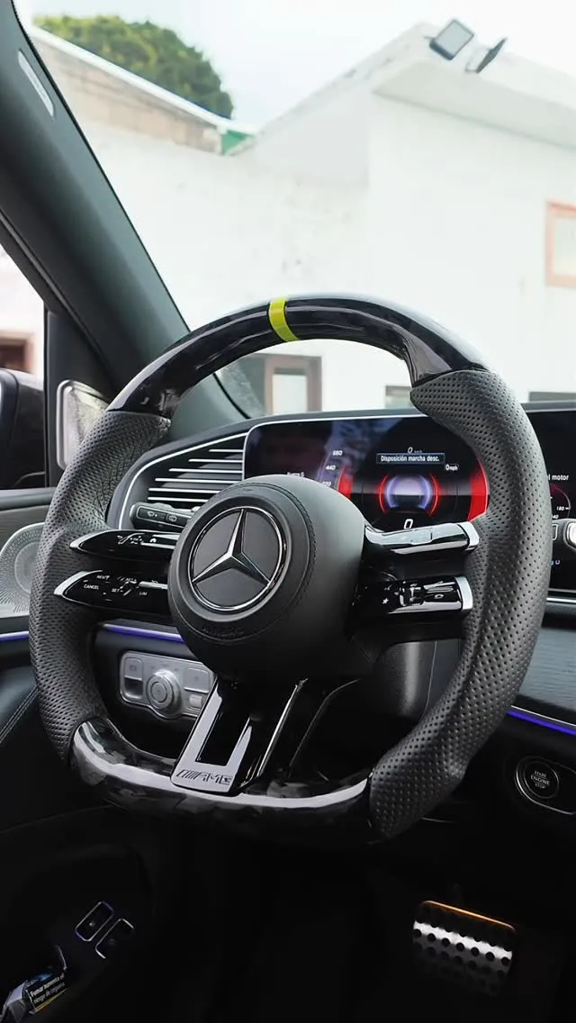 Volante de un Mercedes-AMG con el aro de carbono, las empuñaduras de cuero perforado y una marca amarilla arriba