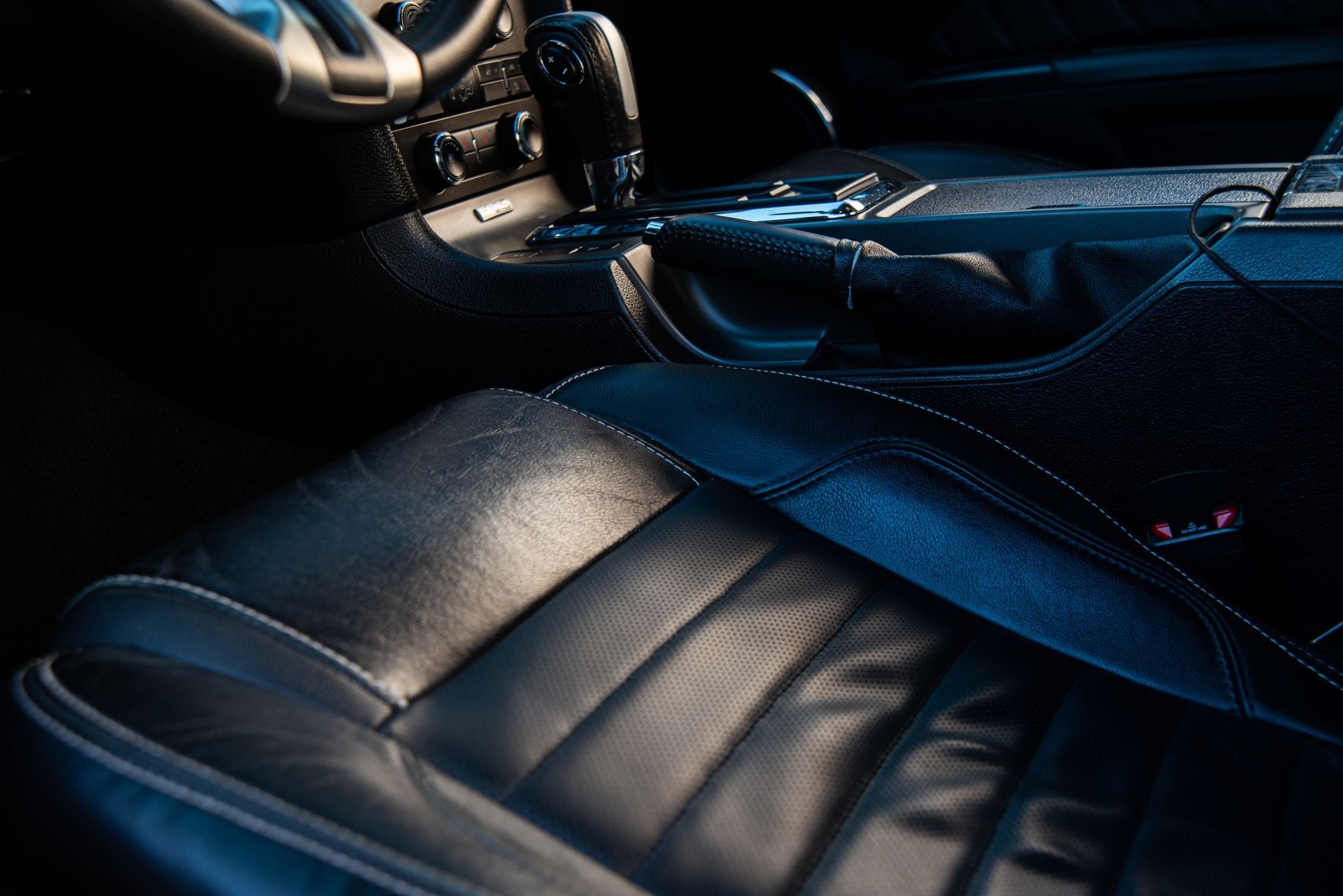 Primer plano del asiento del conductor en cuero negro, con la banqueta marcada por el uso